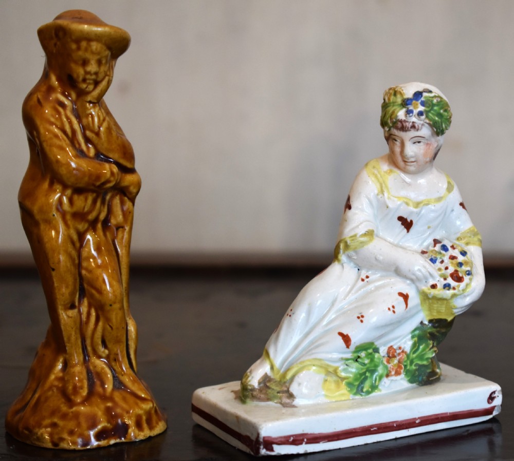 A pair of small early Staffordshire ceramic figures, one standing figure with a brown lead glaze and one seated female figure decorated with colourful hand-painted enamels. View II