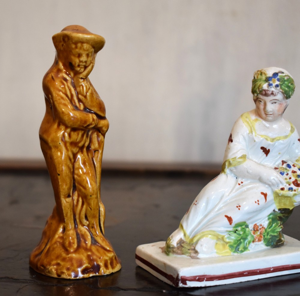 A pair of small early Staffordshire ceramic figures, one standing figure with a brown lead glaze and one seated female figure decorated with colourful hand-painted enamels. View III