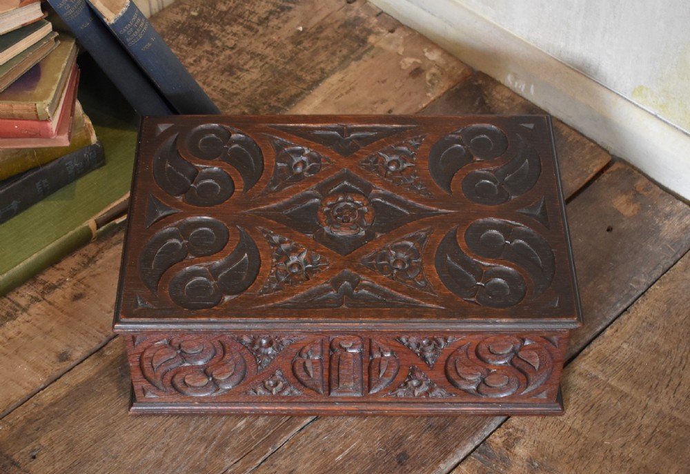 A rectangular dark carved oak box featuring intricate Gothic Revival relief carvings on the top lid and front panels. View II