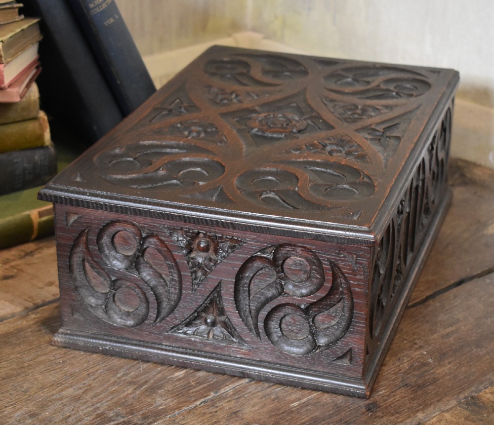 A rectangular dark carved oak box featuring intricate Gothic Revival relief carvings on the top lid and front panels. View IV