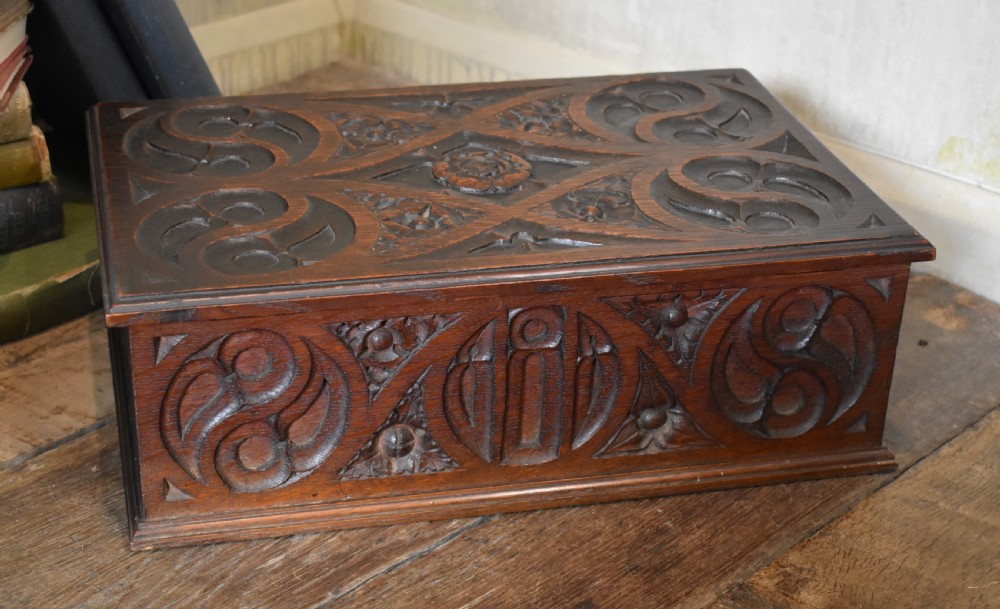 A rectangular dark carved oak box featuring intricate Gothic Revival relief carvings on the top lid and front panels. View VI