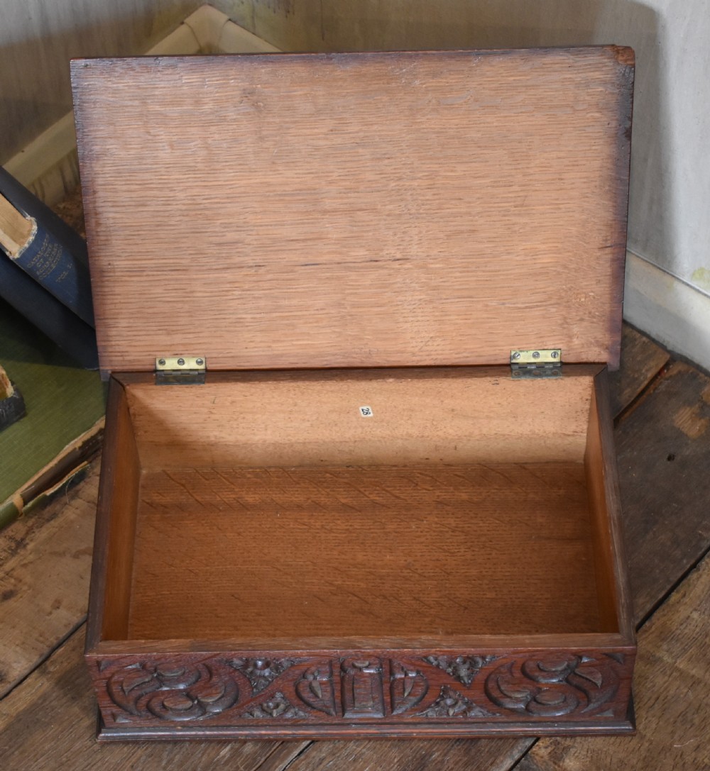A rectangular dark carved oak box featuring intricate Gothic Revival relief carvings on the top lid and front panels. View VII