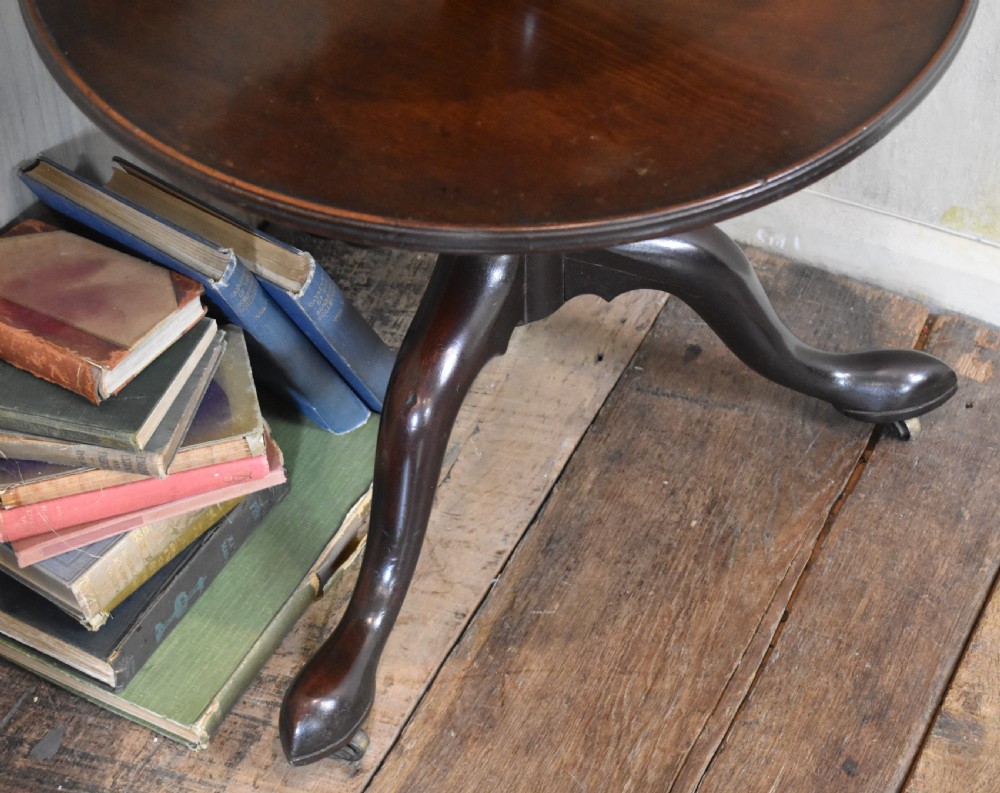 A Georgian mahogany three-tiered dumb waiter with graduated circular trays on a central turned stem supported by tripod cabriole legs with brass castors. View III