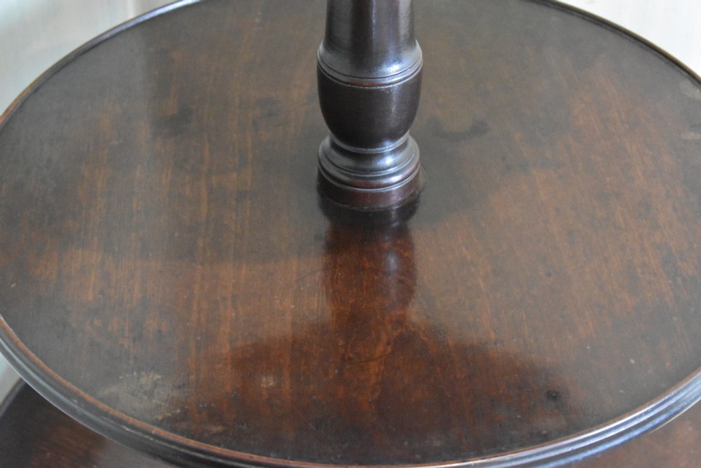A Georgian mahogany three-tiered dumb waiter with graduated circular trays on a central turned stem supported by tripod cabriole legs with brass castors. View IV