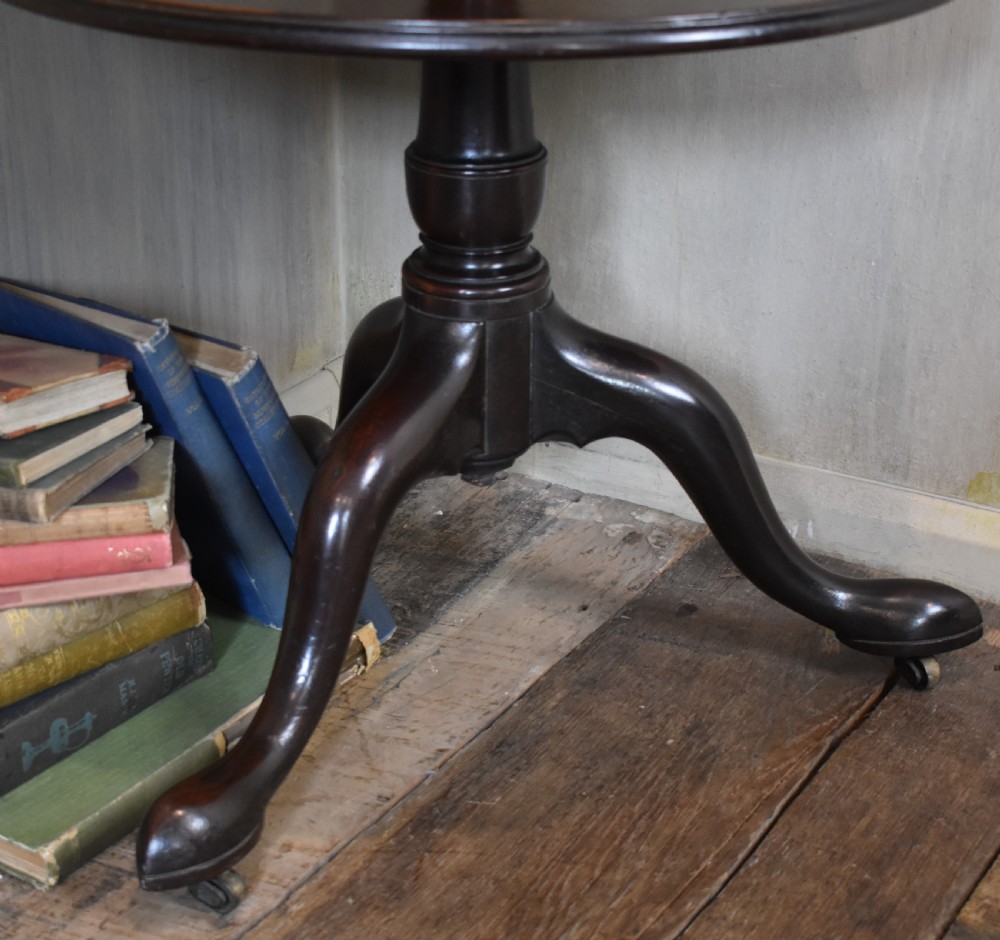 A Georgian mahogany three-tiered dumb waiter with graduated circular trays on a central turned stem supported by tripod cabriole legs with brass castors. View V