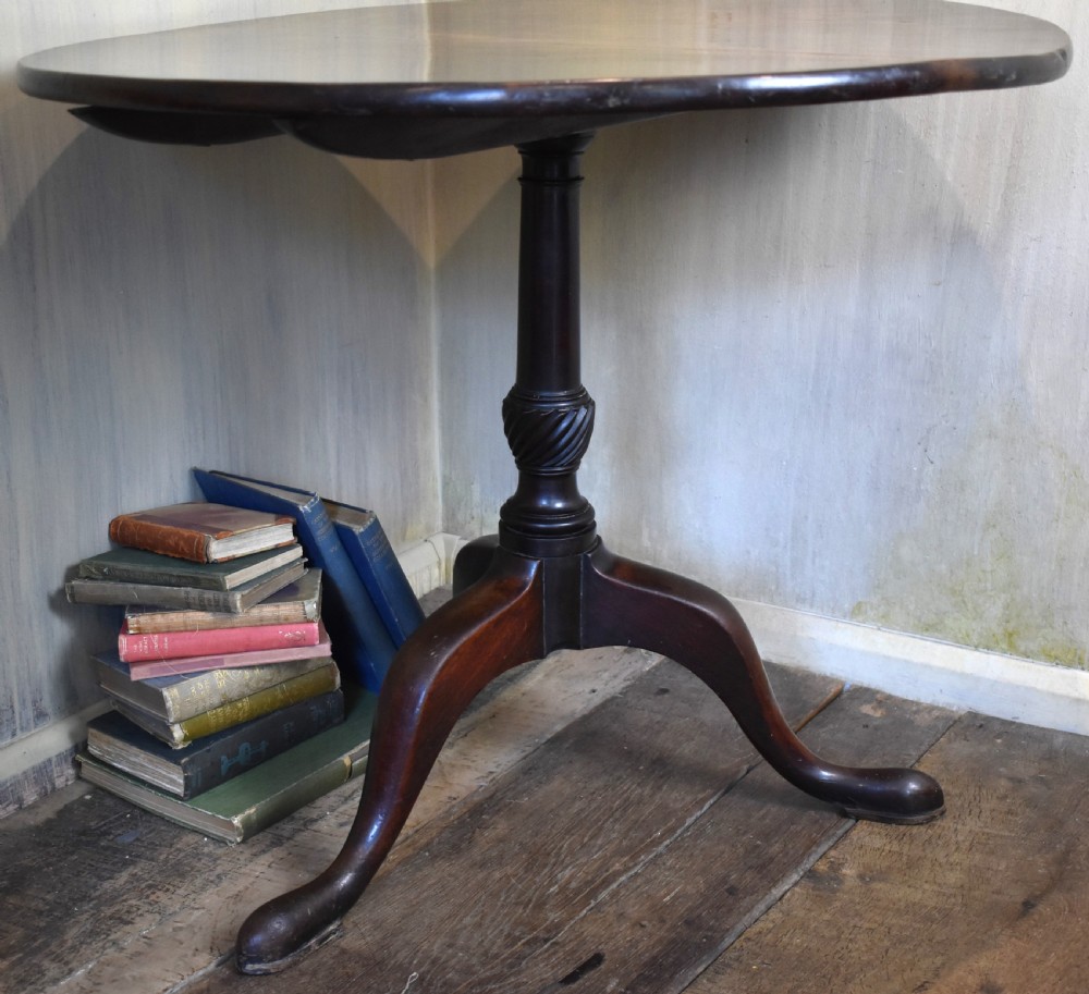 An 18th-century Georgian mahogany tilt-top table featuring a circular surface, a turned central pedestal, and three splayed cabriole legs. View IV