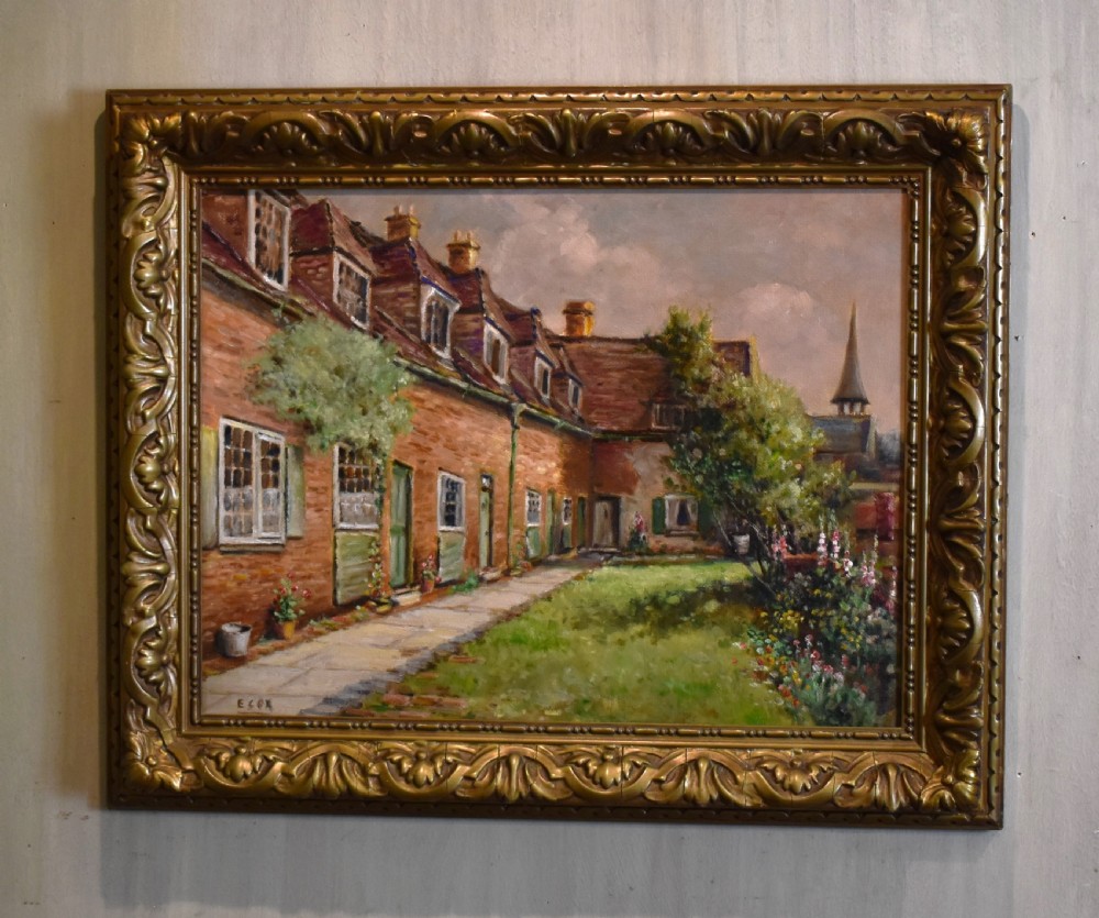 A framed oil painting depicting a row of brick cottages with green shutters alongside a garden path, enclosed in an ornate gilded frame.