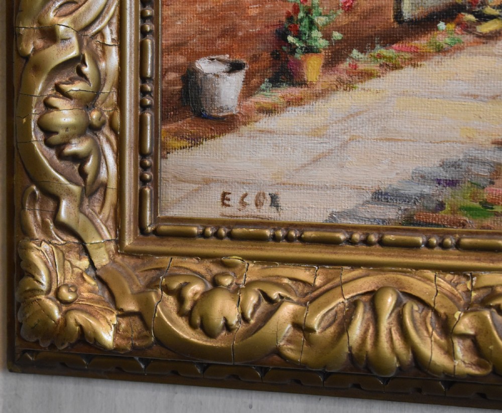 A framed oil painting depicting a row of brick cottages with green shutters alongside a garden path, enclosed in an ornate gilded frame. View III