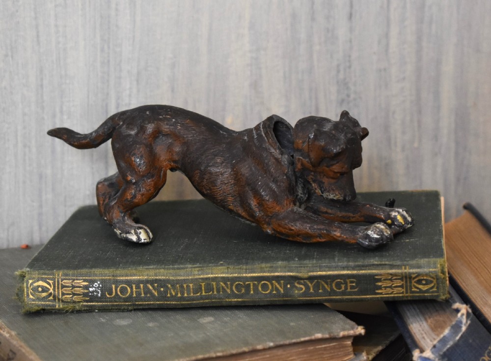 A cold painted spelter figurine depicting a dog in a playful stretching pose with an articulated nodding head mechanism.