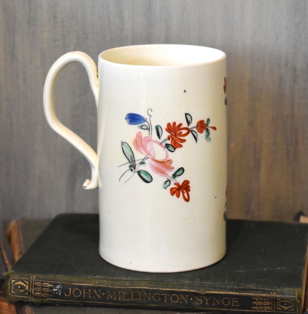 A cylindrical creamware ceramic tankard decorated with hand-painted polychrome floral motifs and a loop handle. View III