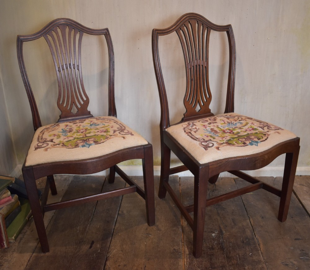 A pair of Georgian mahogany side chairs featuring carved pierced splat backs, serpentine top rails, and embroidered drop-in seats. View II