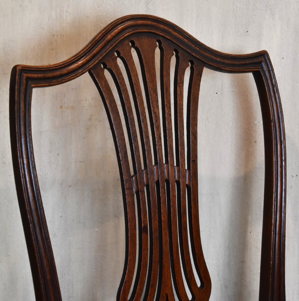 A pair of Georgian mahogany side chairs featuring carved pierced splat backs, serpentine top rails, and embroidered drop-in seats. View III