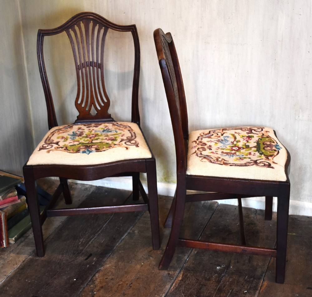 A pair of Georgian mahogany side chairs featuring carved pierced splat backs, serpentine top rails, and embroidered drop-in seats. View IV