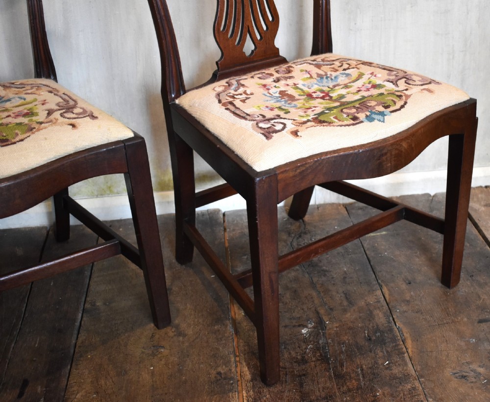 A pair of Georgian mahogany side chairs featuring carved pierced splat backs, serpentine top rails, and embroidered drop-in seats. View V