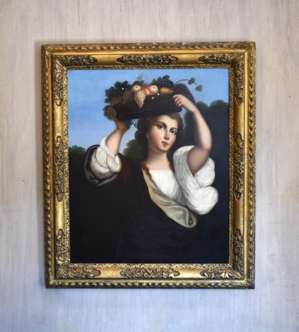 A portrait oil painting depicting a young woman carrying a basket of fruit on her head, set within an ornate carved gilt wood frame.