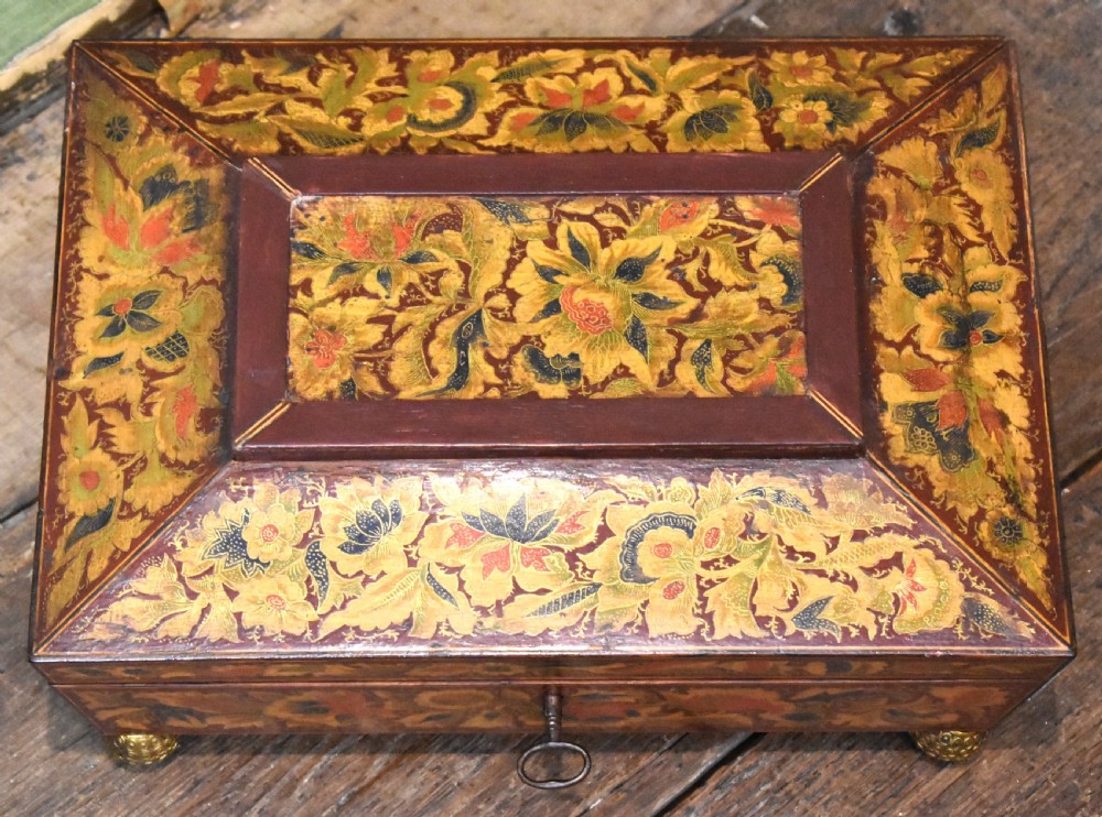A rectangular Regency period wooden box featuring intricate botanical penwork decoration, brass ring handles, and ball feet. View II