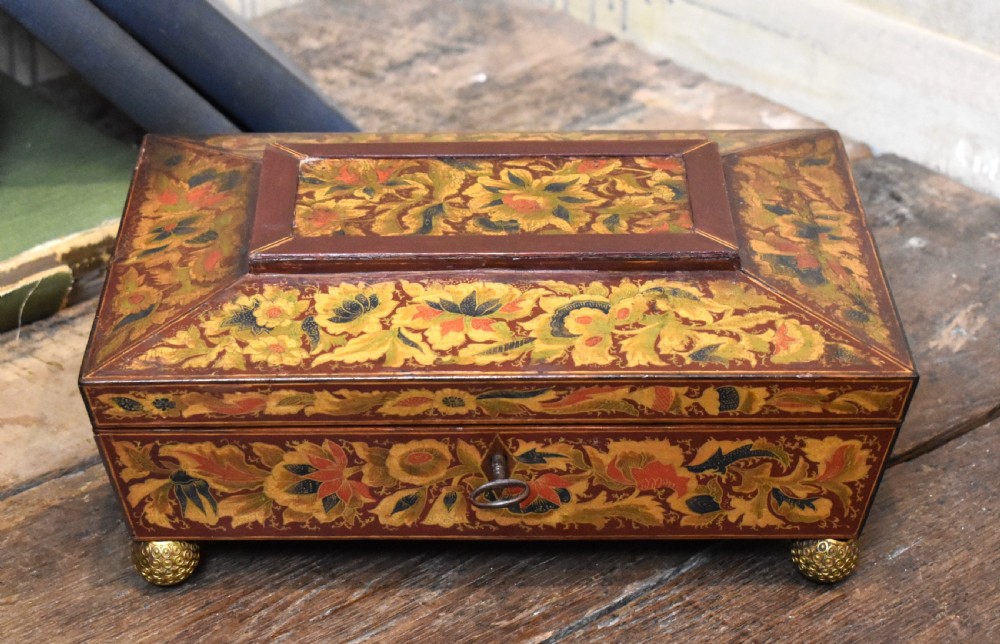 A rectangular Regency period wooden box featuring intricate botanical penwork decoration, brass ring handles, and ball feet. View IV