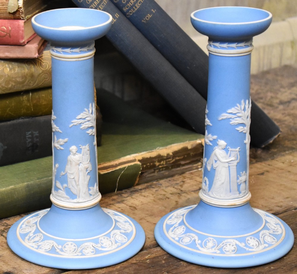 A pair of light blue Wedgwood jasperware candlesticks featuring white neoclassical bas-relief figures and classical floral bands on circular bases. View III