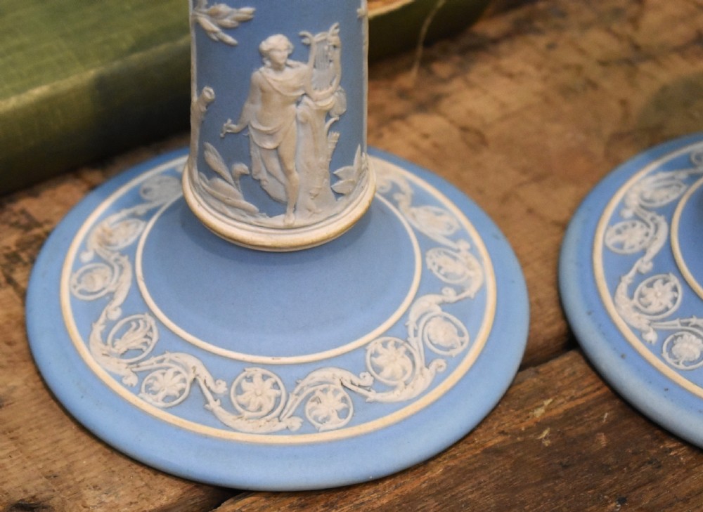 A pair of light blue Wedgwood jasperware candlesticks featuring white neoclassical bas-relief figures and classical floral bands on circular bases. View IV