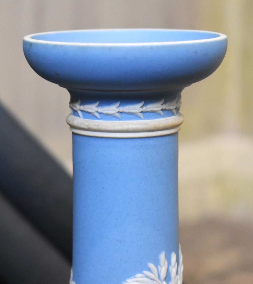 A pair of light blue Wedgwood jasperware candlesticks featuring white neoclassical bas-relief figures and classical floral bands on circular bases. View V