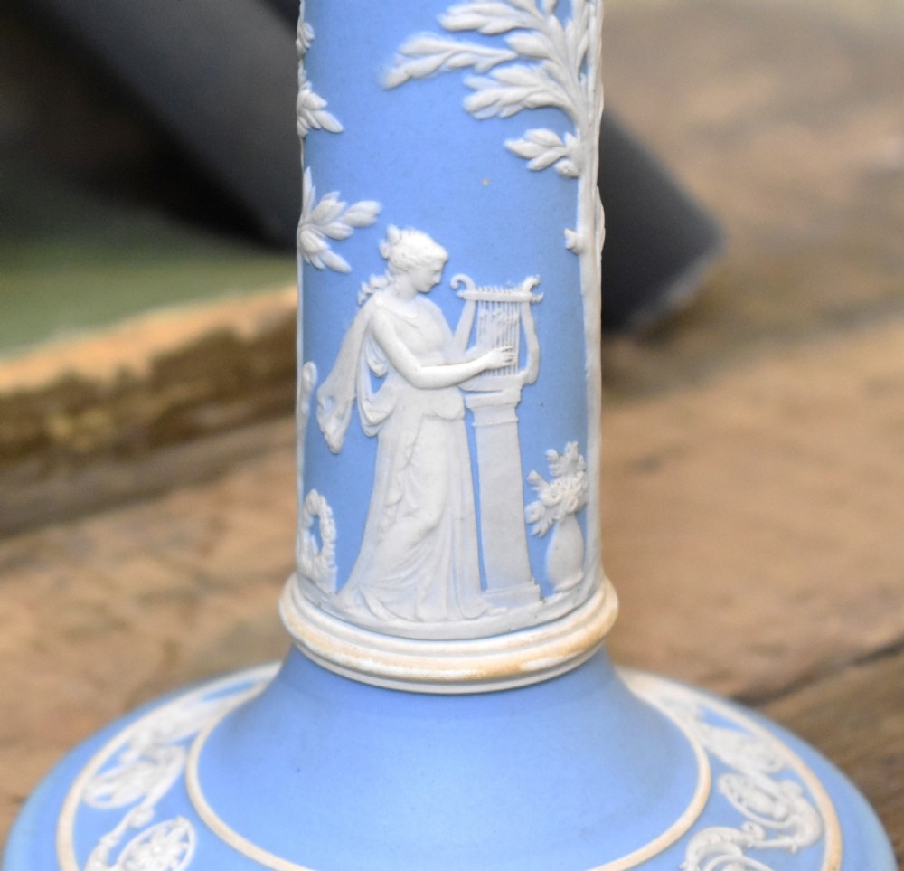 A pair of light blue Wedgwood jasperware candlesticks featuring white neoclassical bas-relief figures and classical floral bands on circular bases. View VIII