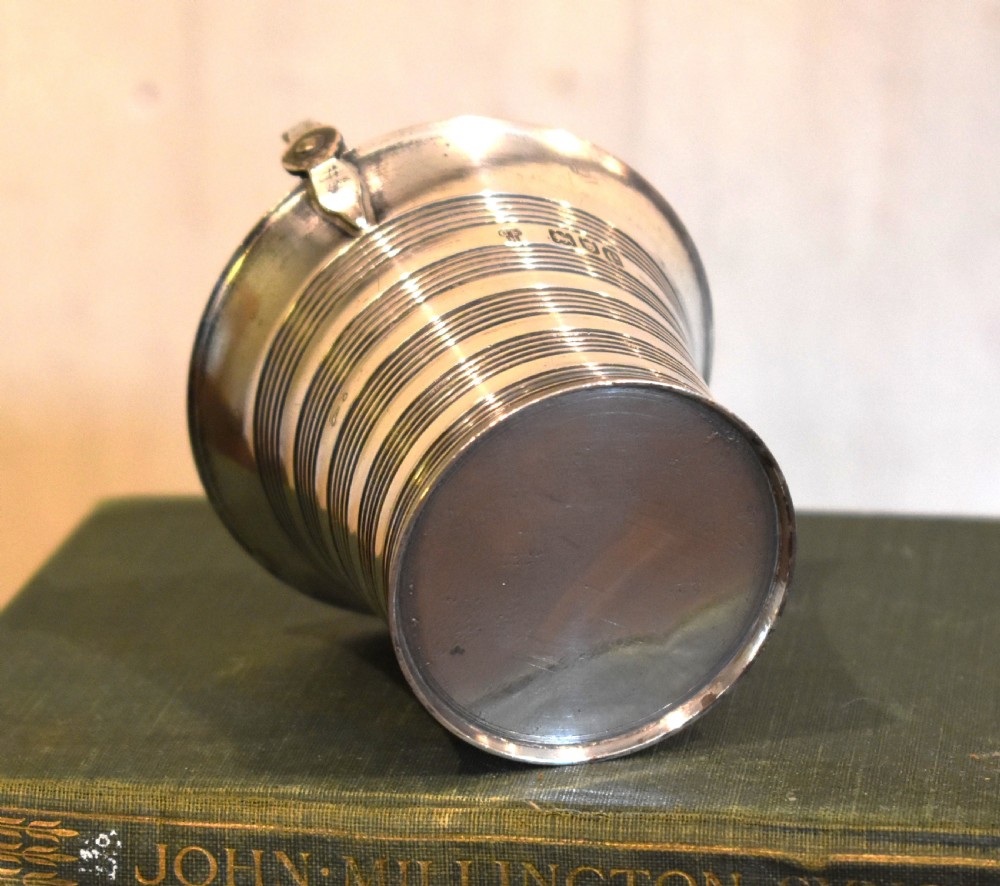 A solid silver miniature bucket pail featuring horizontal reeded detailing, visible hallmarks on the exterior, and a twisted swing handle. View V