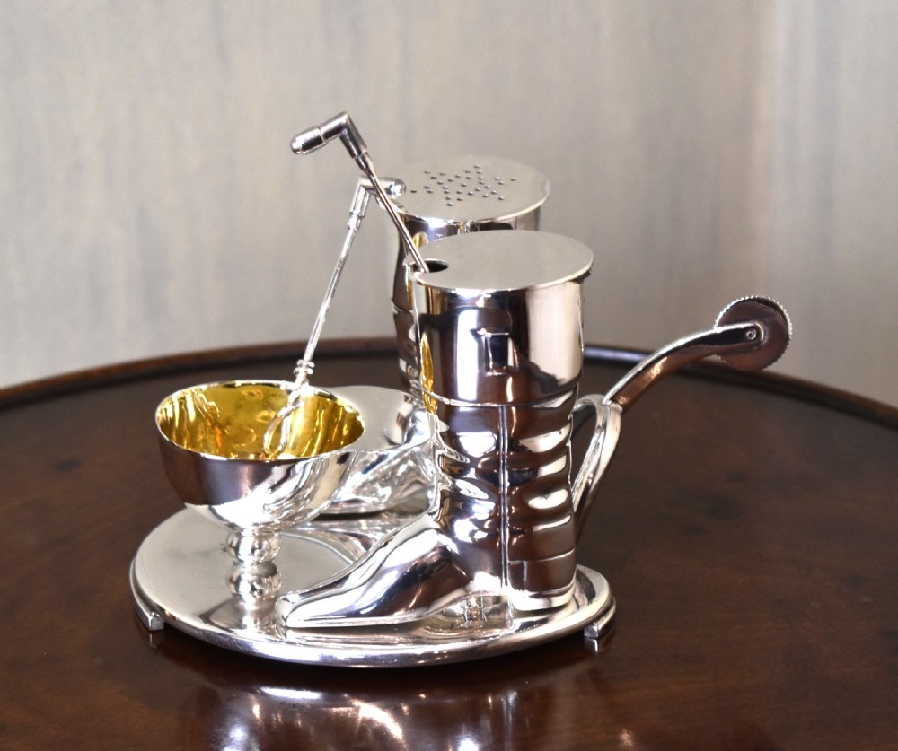 A silver-plated novelty equestrian cruet set featuring a riding boot mustard pot with a spur handle, a cap pepper shaker, and a gilt-lined salt cellar on a fitted tray.