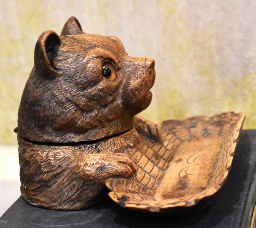 A carved wooden Black Forest inkwell featuring the detailed head of a cat with glass eyes positioned behind a basketweave pen tray. View III