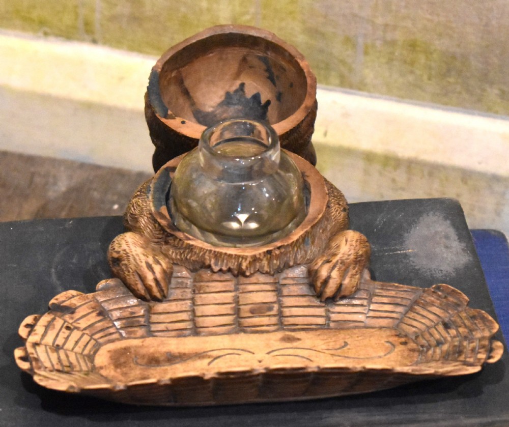 A carved wooden Black Forest inkwell featuring the detailed head of a cat with glass eyes positioned behind a basketweave pen tray. View IV