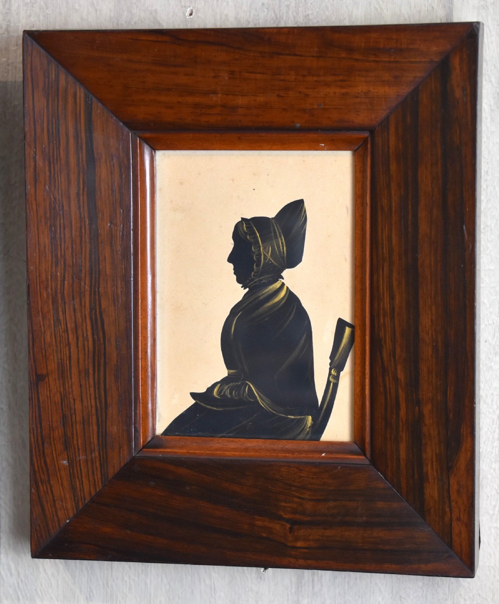 A pair of framed Victorian profile silhouettes depicting a man and a woman in polished dark wood frames. View V