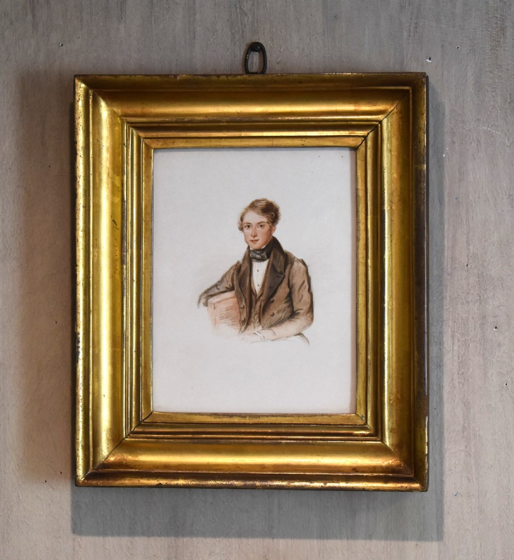 A 19th-century watercolour portrait of a gentleman wearing a dark cravat and jacket, set inside a heavy moulded gilded wood frame with a hanging loop.