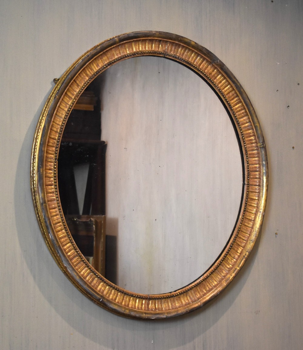 Large early nineteenth century oval gilt mirror