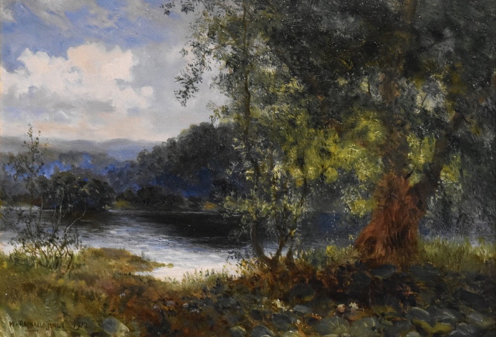 A framed oil painting depicting a tranquil river scene with leafy green trees, distant hills, and a cloudy blue sky, encased in a gold gilded wooden frame. View IV