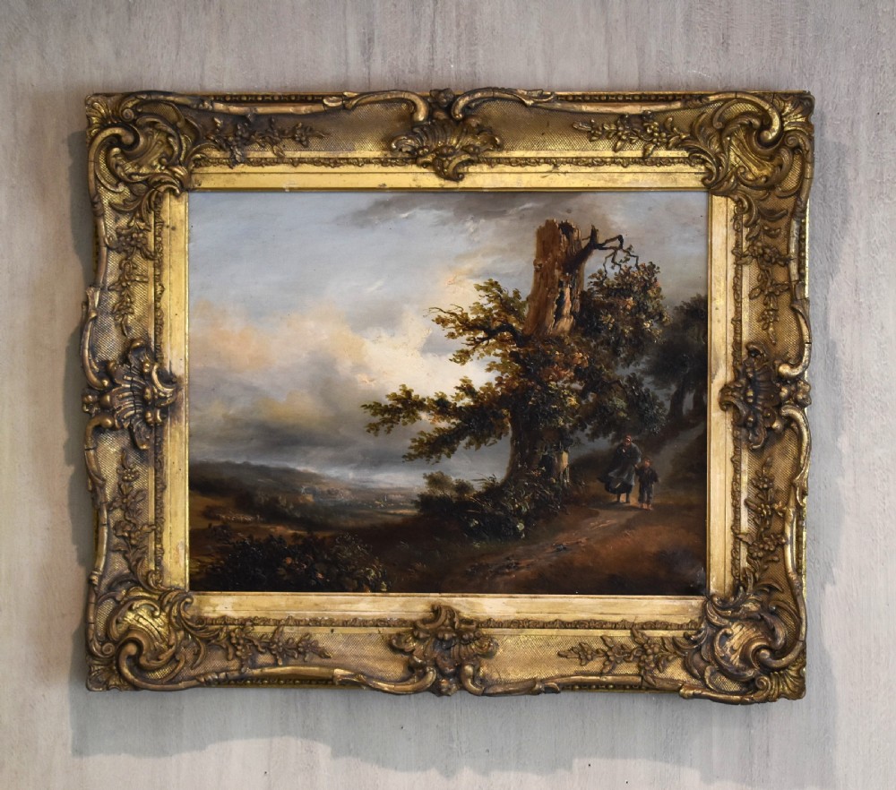 A nineteenth-century French oil painting depicting figures beside a prominent oak tree in a atmospheric rural landscape, presented in a ornate gilded gesso frame.