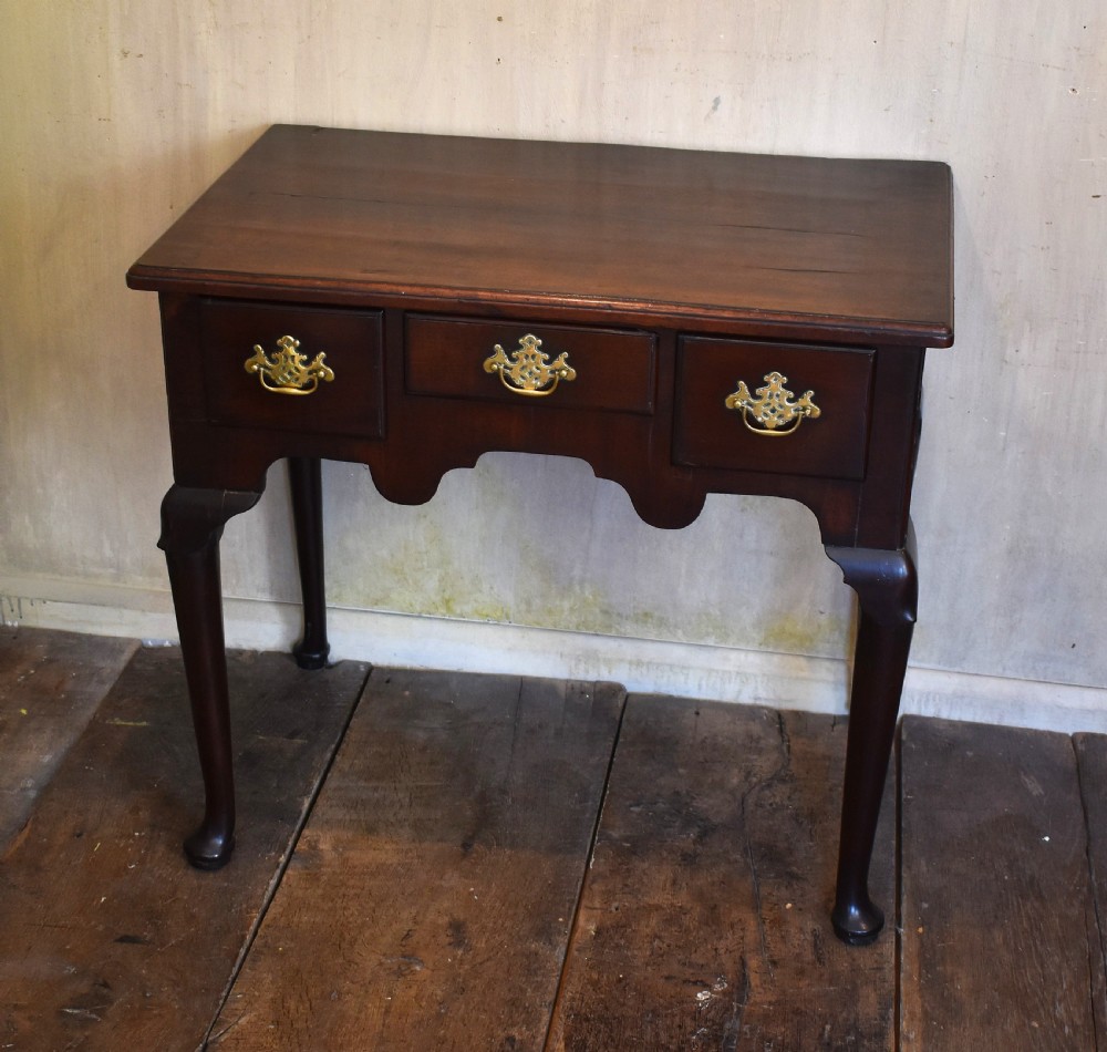 A Georgian mahogany lowboy featuring three drawers fitted with pierced brass batwing handles, a shaped apron, and pad feet on cabriole legs. View II