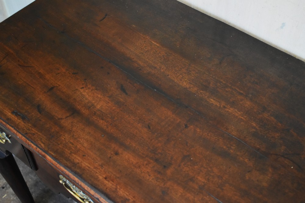 A Georgian mahogany lowboy featuring three drawers fitted with pierced brass batwing handles, a shaped apron, and pad feet on cabriole legs. View III