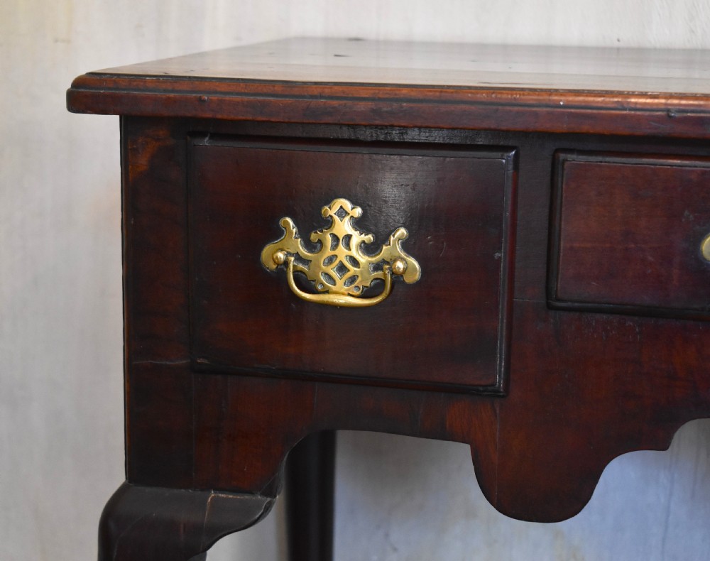 A Georgian mahogany lowboy featuring three drawers fitted with pierced brass batwing handles, a shaped apron, and pad feet on cabriole legs. View IV