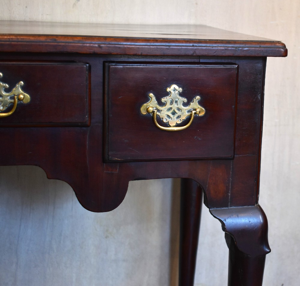 A Georgian mahogany lowboy featuring three drawers fitted with pierced brass batwing handles, a shaped apron, and pad feet on cabriole legs. View V