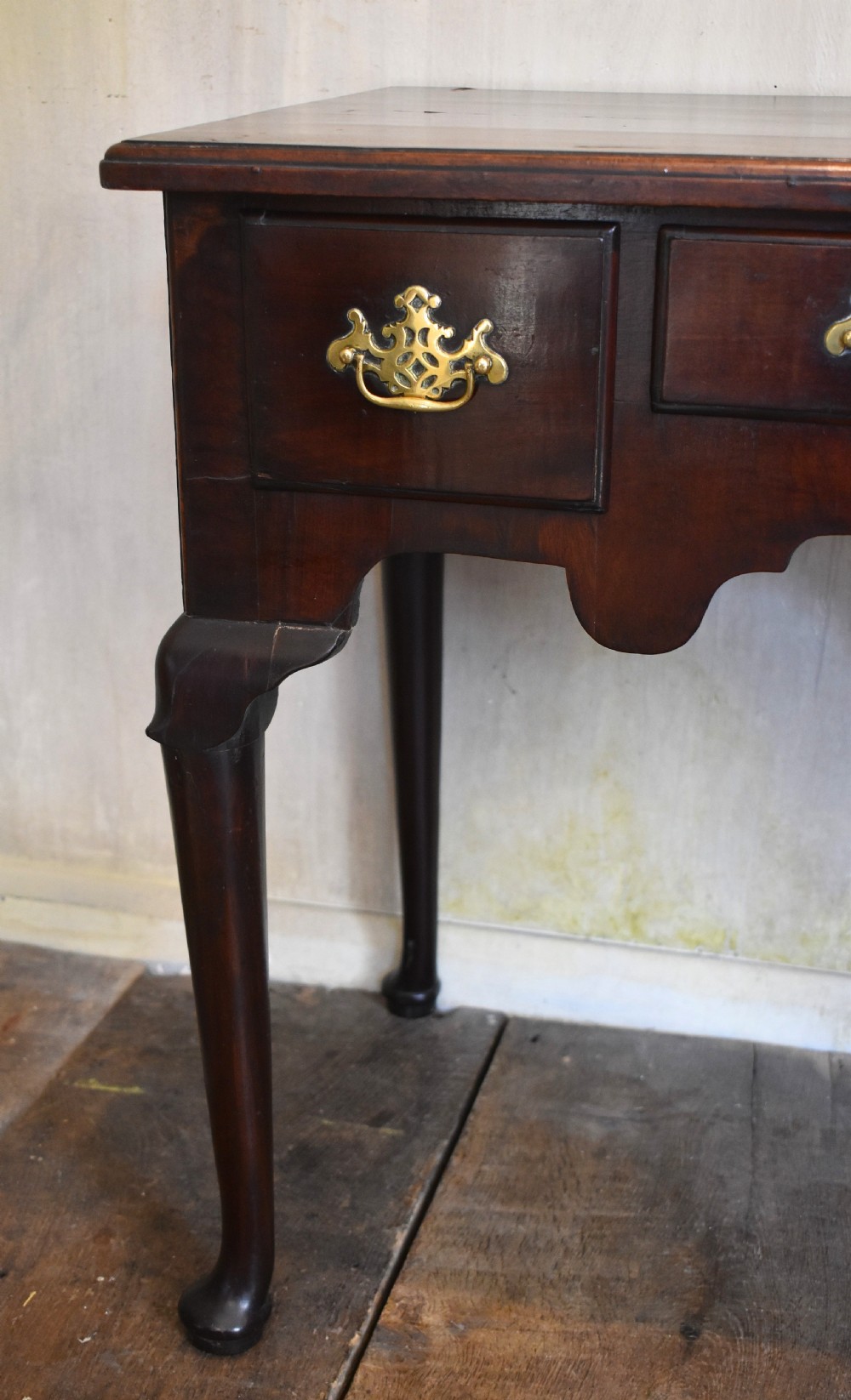 A Georgian mahogany lowboy featuring three drawers fitted with pierced brass batwing handles, a shaped apron, and pad feet on cabriole legs. View VI