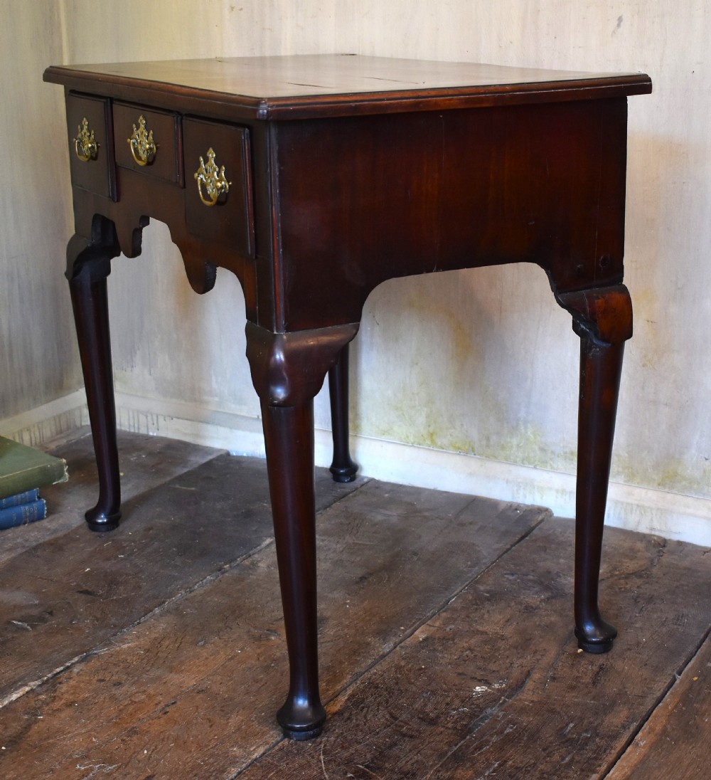 A Georgian mahogany lowboy featuring three drawers fitted with pierced brass batwing handles, a shaped apron, and pad feet on cabriole legs. View VII