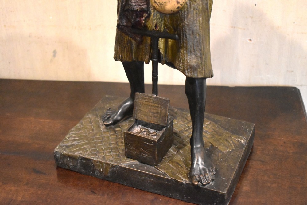 A patinated bronze sculpture depicting an Arab merchant standing over a small wooden box and holding items in draped robes. View V