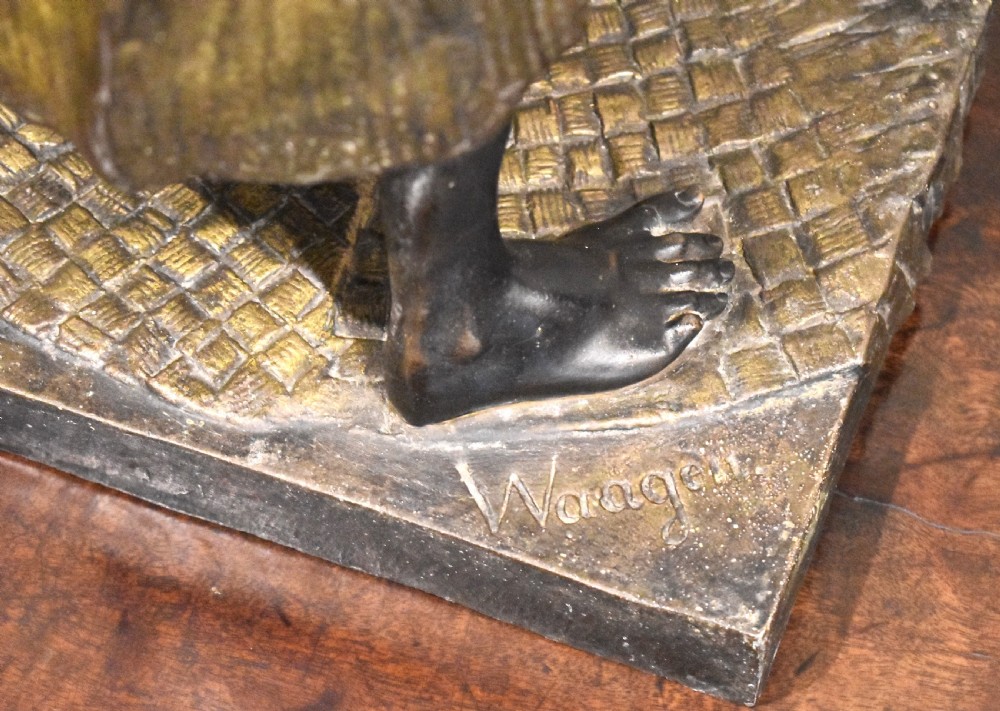 A patinated bronze sculpture depicting an Arab merchant standing over a small wooden box and holding items in draped robes. View VII