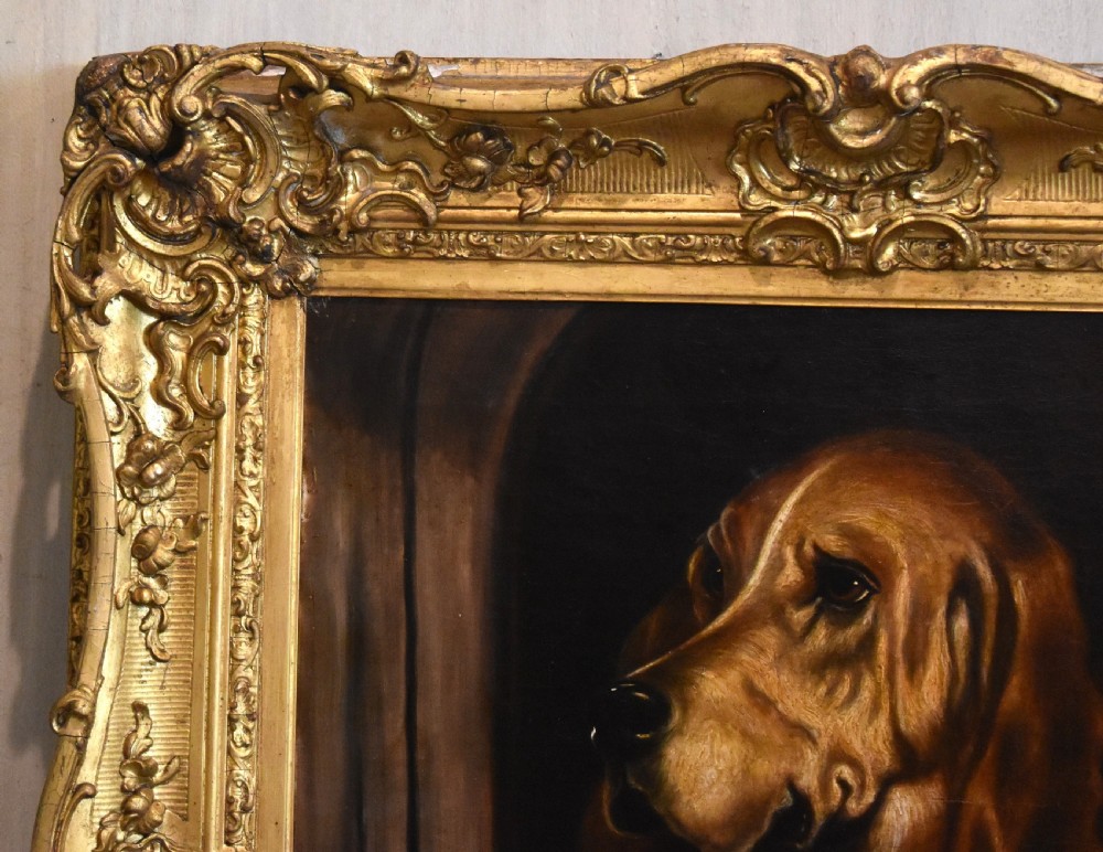 An oil painting depicting a large brown hound and a small white terrier peering from a dark wooden structure within a carved gold frame. View V