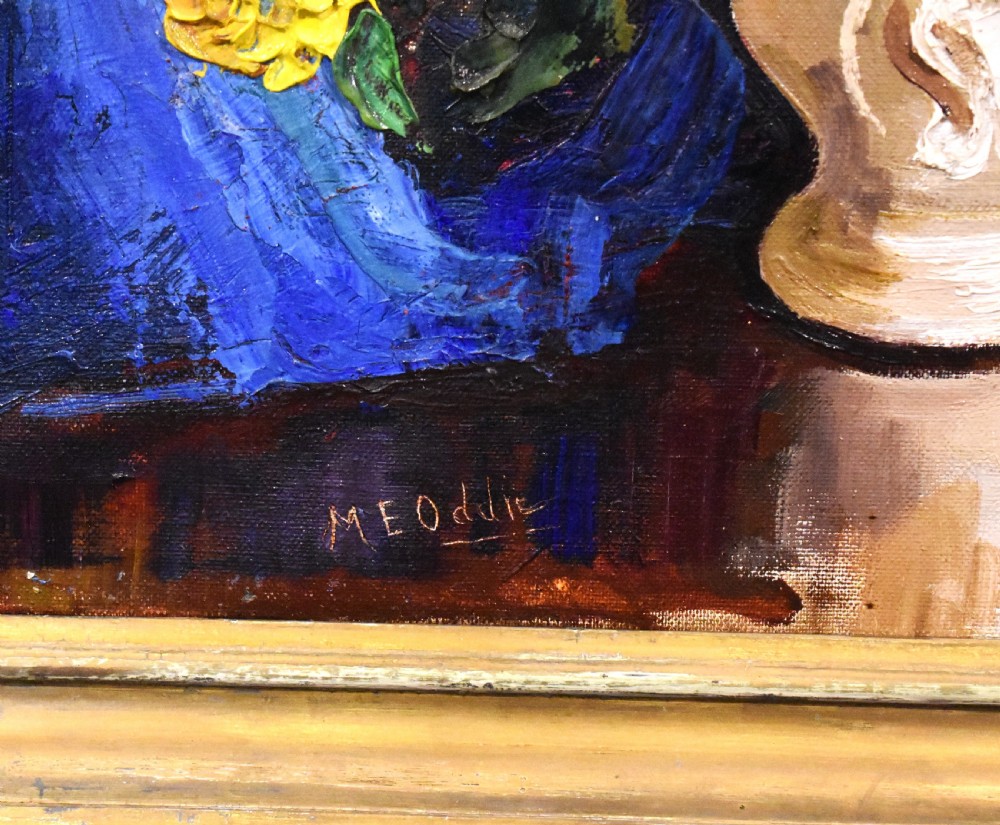 A framed oil painting featuring a vase filled with colourful flowers beside a draped blue cloth set against a dark background. View V