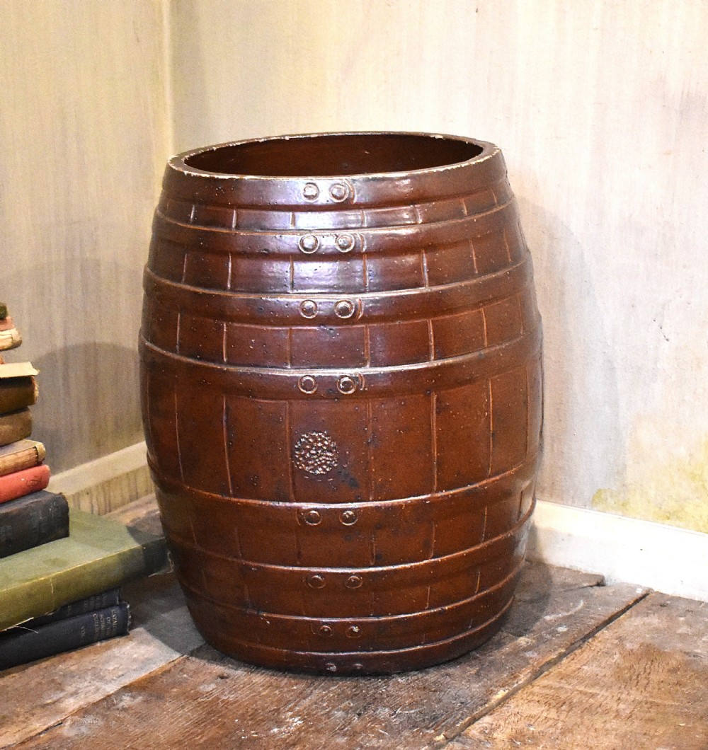 A large dark brown saltglaze stoneware stick stand moulded in the shape of a barrel with simulated staves and metal hoops.