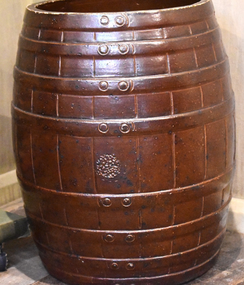 A large dark brown saltglaze stoneware stick stand moulded in the shape of a barrel with simulated staves and metal hoops. View II