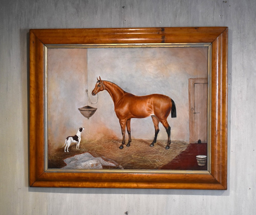 An antique oil painting depicting a chestnut horse and a small dog inside a stable setting, presented in a polished timber frame with a gold inner slip.