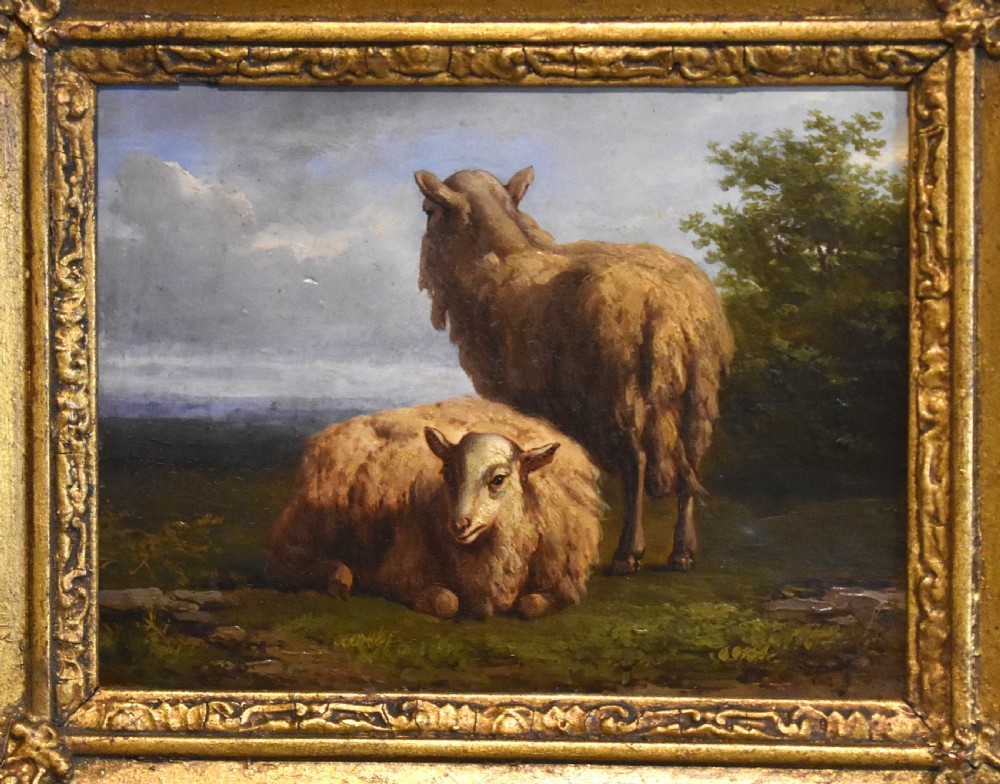 A small 19th-century pastoral oil painting depicting two sheep in a landscape, set within an ornate gilded frame with scrolled corner detailing. View III