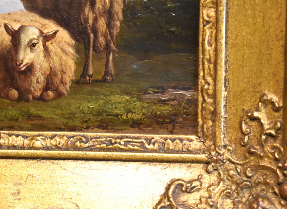 A small 19th-century pastoral oil painting depicting two sheep in a landscape, set within an ornate gilded frame with scrolled corner detailing. View V