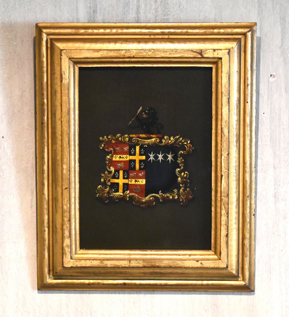 An oil-painted Georgian heraldic coat of arms within a Rococo cartouche, framed in a moulded giltwood frame.